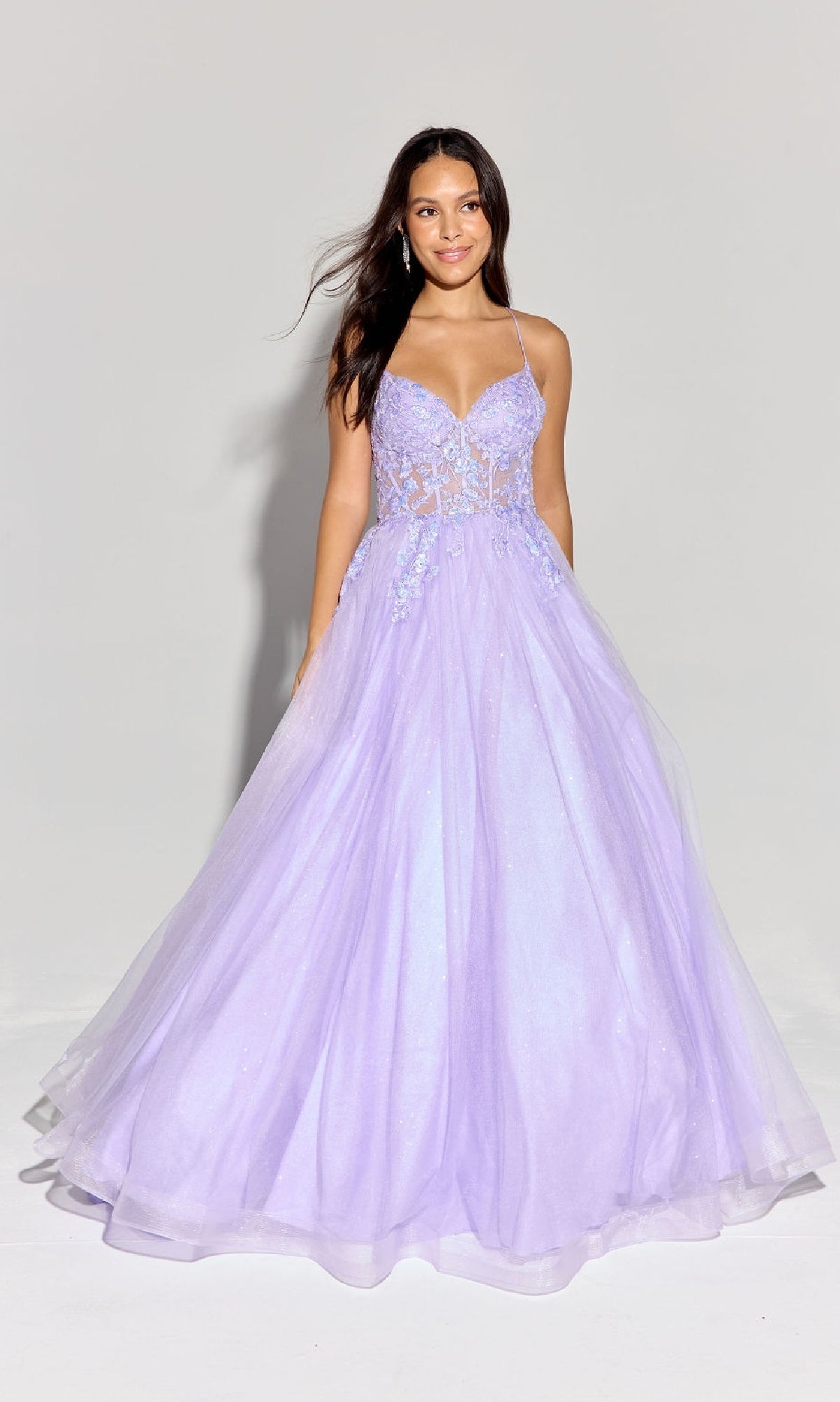 A woman wears the Eureka 9960 Lace-Up Corset Long Prom Ball Gown, featuring a fitted, semi-sheer bodice with floral accents and a full tulle skirt in lavender.